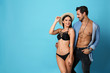 © New Africa - Beautiful young woman in stylish bikini and man on light blue background. Space for text