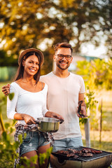 Portrait of a happy young hipster couple having barbecue outdoors.