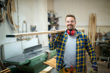 Professional Smiling Middle Aged Carpenter Holding Wood Plank In Woodworking Workshop.