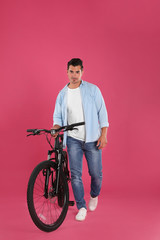 Poster - Handsome young man with modern bicycle on pink background