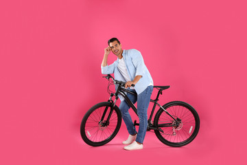 Poster - Handsome young man with modern bicycle on pink background