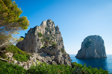 Bright Scenic View Of The Iconic Faraglioni Rocks From The Nearby Cliffside Trail On The Mediterranean Island Of Capri, Italy