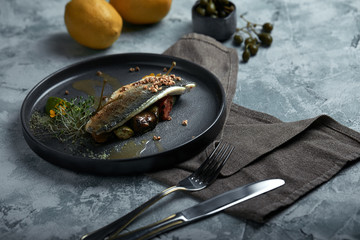 Grilled seabass with eggplant and lime. Horizontal top view, top shot. Copy space, gray concrete marble background, soft light. Food Fashion Photo.