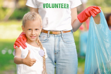 Wall Mural - Little volunteer with woman gathering garbage in park