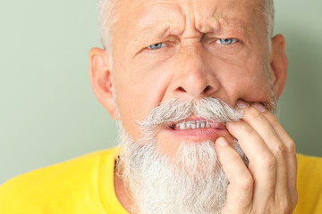 Wall Mural - Senior man suffering from toothache against color background, closeup