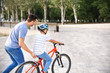 © Pixel-Shot - Father teaching his son to ride bicycle outdoors