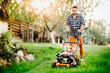 © aboutmomentsimages - Garden and grass maintainance details - close up view of grass mower and worker .