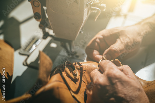 Working process of leather craftsman. Tanner or skinner sews leather on a special sewing machine, close up