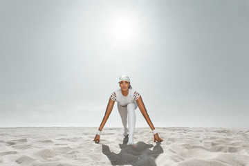 Wall Mural - Fit woman sprinter, start running at the desert wearing in white sportswear. Fitness and sport motivation. Runner concept with copy space.