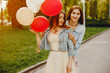 © hetmanstock2 - two young and bright girls spend their time in the summer park with balloons