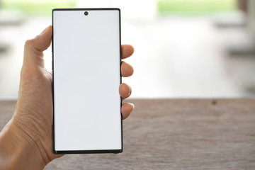 the man's hand is holding a new smartphone.