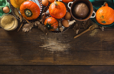 Poster - Raw ingredients for cooking pumpkin pie with dry autumn leaves on wooden background with copy space