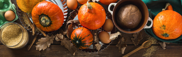 Poster - Raw ingredients for cooking pumpkin pie with dry autumn leaves on wooden table close up