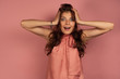 © bestsenny - A dark-haired girl in a pink dress stands on a pink background with her hands on her head, her mouth wide open.