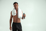 Fototapeta Przeznaczenie - It was great workout Handsome and cheerful african man with towel on shoulders and naked torso looking at camera and smiling while standing against grey background