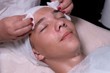 © romsvetnik - Face of a teenage boy with closed eyes. A beautician wipes a guy's cheeks and forehead with cotton pads. Dermatological procedure for cleansing teenager acne skin in a spa. Hygiene and personal care.