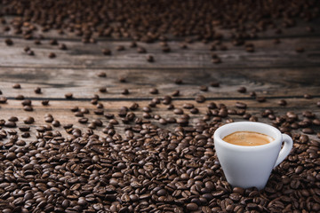 White cup of coffee espresso with beans on brown wooden table