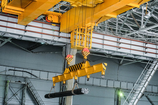 yellow overhead crane carries cargo in engineering plant shop. jib crab trolley with hooks and linea