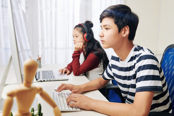 Wall Mural - smart serious mixed-race teenagers working on computers in class in school