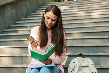 Wall Mural - Attractive young smiling girl student reading a book