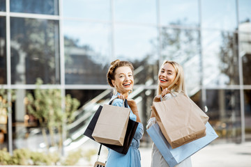 Wall Mural - Portrait of a two happy women with shopping bags standing in front of the shopping mall