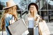 © rh2010 - Two happy girlfriends walking with shopping bags in front of the shopping mall, feeling satisfied with new purchases