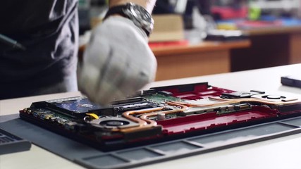 Wall Mural - Computer solid state drive upgrade, diagnosing breakdowns. Technician detaches laptop hard drive ssd repairing it in service center workshop, hands closeup. He unscrews bolts in computer screwdriver.