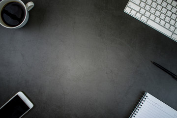 Top view of modern black desk with accessories and copy space in the middle of the image.