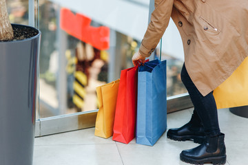 Woman puts the packages on the floor in the shopping mall. The face is not visible. Buying too much concept.Time for shopping, copy space on the left side