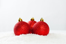 Three Red Baubles On White Snow Background. Christmas Composition