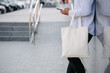 © 4Max - Young man holding white textile eco bag against urban city background. . Ecology or environment protection concept. White eco bag for mock up.
