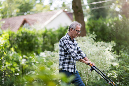 Fotomural  Elderly man mowing the lawn