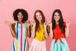 © Drobot Dean - Smiling young three multiethnic girls friends posing isolated over pink wall background holding little fingers pinky of each other.