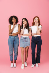 Wall Mural - thinking thoughtful cute multi-ethnic girls friends posing isolated over pink wall background.