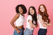 © Drobot Dean - Cheery smiling positive young three multiethnic girls friends posing isolated over pink wall background.