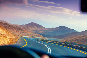 Driving a car on the mountain road in the desert. View of sandstone mountains through the windscreen. The road from Arad to the Dead Sea. Israel