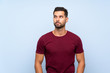 © luismolinero - Handsome man over isolated blue background making doubts gesture looking side