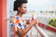 Young african american girl holding burger in her hands outdoor and posing for camera.