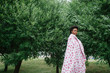 Beautiful dark skinned girl wrapped in sheet with fashion print posing at park with trees on background.