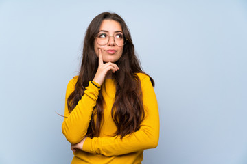 Wall Mural - teenager girl over isolated blue wall thinking an idea