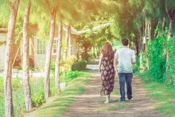 Couple walking and taking photos under the pine trees in the public park.