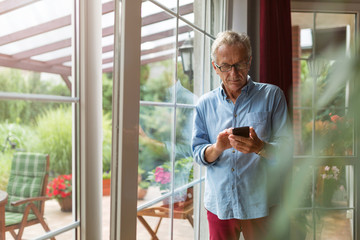 Wall Mural - Senior man using mobile phone at home