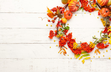 Autumn concept with pumpkins, flowers, autumn leaves and  rowan berries on a white rustic background. Festive autumn decor, flat lay with copy space.