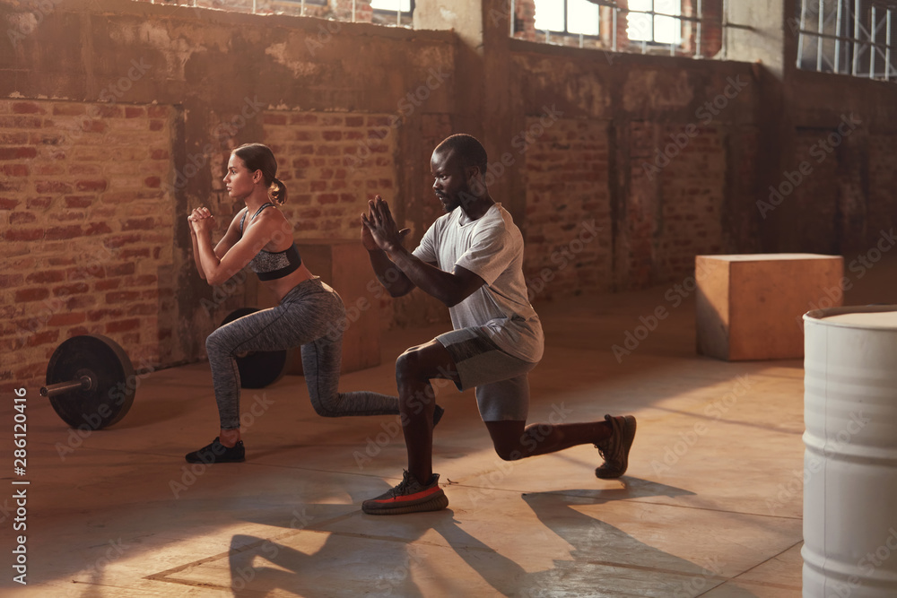 Sport couple doing leg lunge exercise workout at gym - obrazy, fototapety, plakaty 