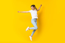 Young Woman Jumping Over Isolated Yellow Wall