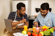 © liliyabatyrova - Two men using laptop in kitchen