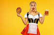 © Mike Orlov - Young sexy Oktoberfest girl waitress, wearing a traditional Bavarian or german dirndl, serving big beer mugs with drink and bretzel, isolated on yellow background. Wow emotion.