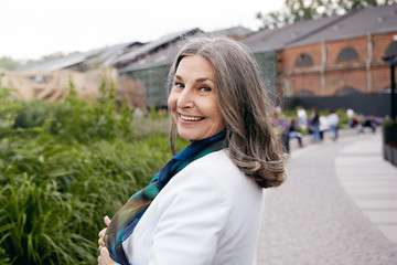 Joy, happiness and modern lifestyle concept. Rear view of attractive fashionable middle aged woman turning head, looking at camera with radiant happy smile, enjoying retirement, having walk