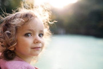 Close-up portrait of small girl standing in nature. Copy space.