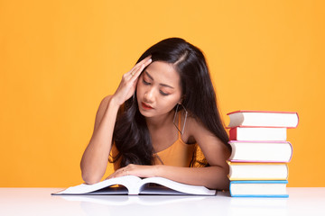 Exhausted Young Asian woman read a book with books on table.